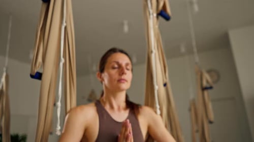 Woman Meditating in Aerial Yoga Hammock Indoors