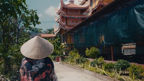 Tourist Wearing Traditional Vietnamese Conical Hat Exploring Ornate Temple with Vibrant Decorations
