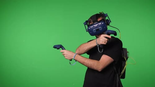 A Man Uses Virtual Reality Glasses to Play in a Studio on a Green Background