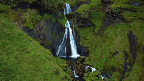 Aerial landscape view of Uxafótafoss waterfall, Iceland, flowing down a rocky cliff covered in dark