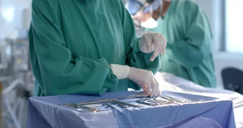 Midsection of female surgeon preparing surgical instruments in theatre, copy space, slow motion