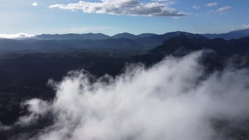 Overhead perspective capturing hill embraced by low-hanging clouds