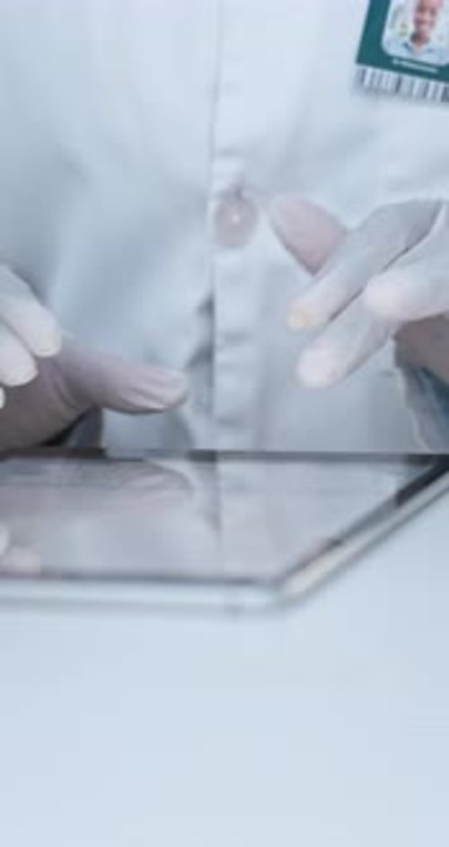 Person Using Tablet in Lab with White Gloves