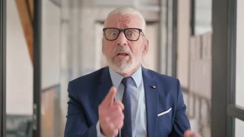 Senior Man Gesturing Angrily in Office Setting