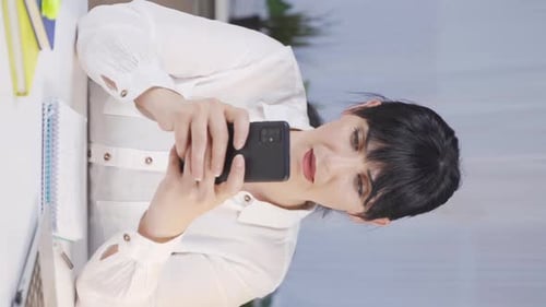 Woman Using Phone at Desk in Bright Office