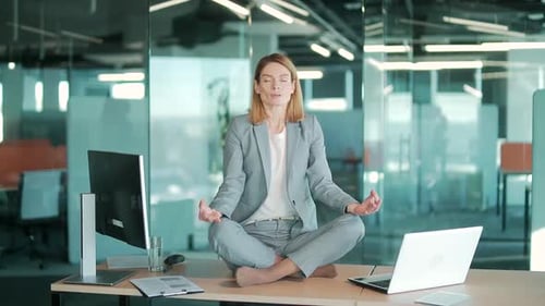 Businesswoman doing yoga to calm down the stressful emotion from hard work in office over desk