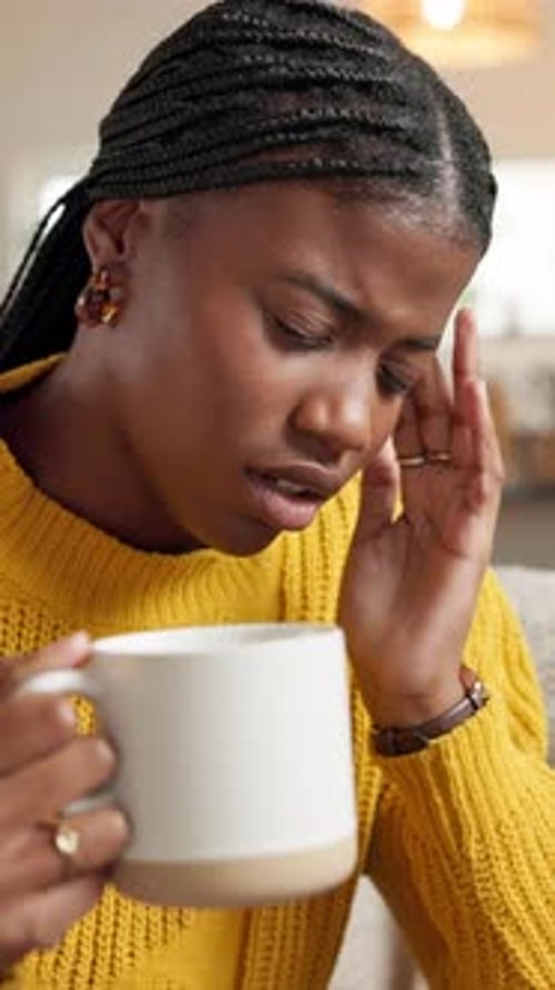 Stressed Woman Holding Mug with Hand on Temple