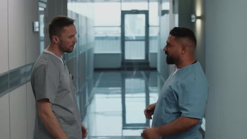 Hospital Workers Having Talk and Shaking Hands in Corridor