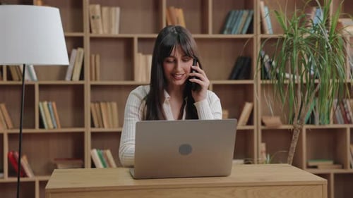 Woman Using Laptop and Talking on Cell Phone