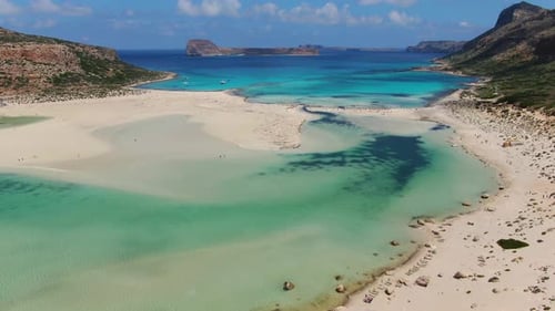 Balos Beach saltwater lagoon in Crete Greece with bathing tourists below, Aerial high up dolly in sh