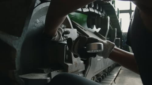 Hands of Female Mechanic Fixing Wheel on Continuous Tracked Vehicle with Wrench