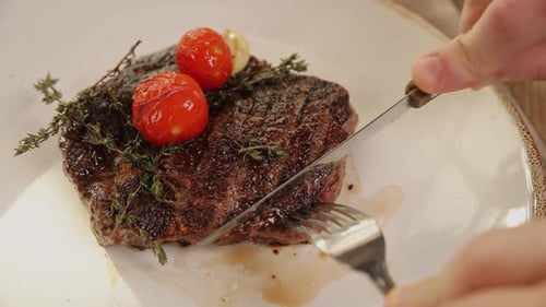 Cutting Into Seasoned Steak with Tomatoes and Thyme