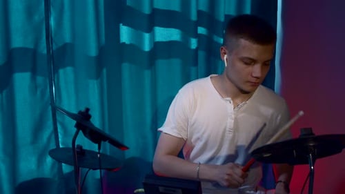 A handsome guy playing drums with his earphones in a recording studio
