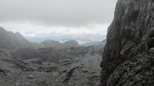 Dramatic Mountain Landscape Showcasing Rocky Terrain and Distant Peaks with Shifting Clouds and