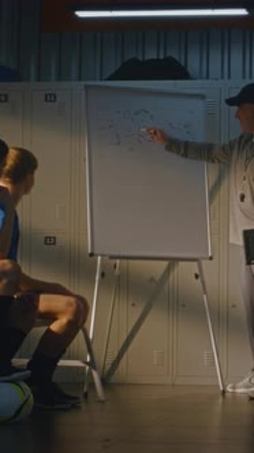 Serious Sports Coach Giving Tactical Lecture to Teenage Soccer Players