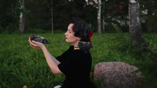 Uma mulher está interagindo alegremente com vários pássaros em um ambiente natural sereno e bonito ao ar livre