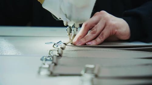 Seamstress hands sewing fabric with machine