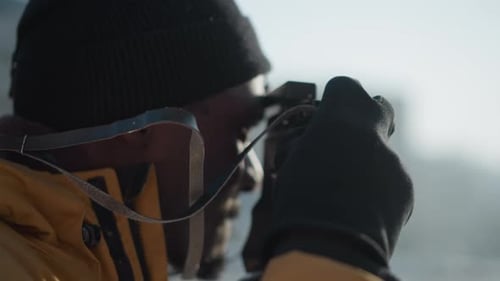 Back View Photographer Adjusting Camera Lens on Snowy Path Under Sun