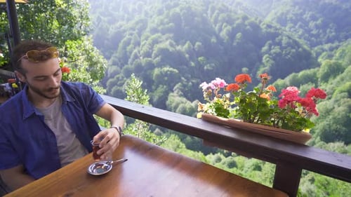Man Relaxing with Drink at Mountain View Balcony