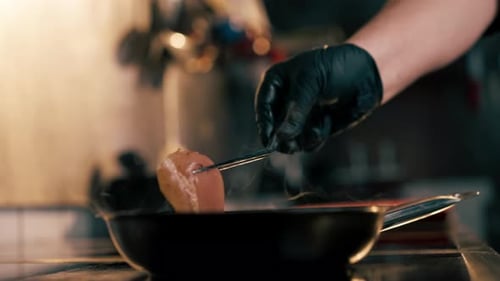Gloved Chef Frying Meat in Steaming Pan