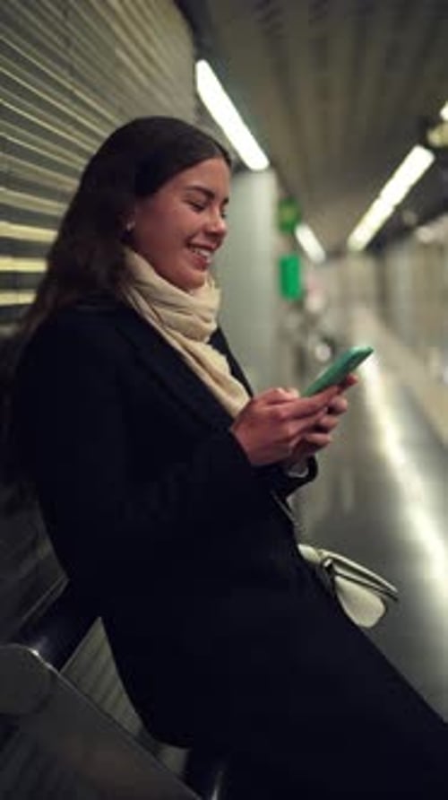 Thoughtful Woman Using Smartphone While Waiting for Transport at Subway Station Engaged in Browsing