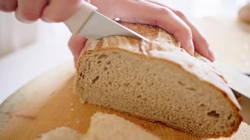 Hands Slice Fresh Bread Loaf on Cutting Board