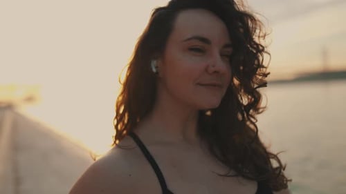 Woman with Curly Hair Standing Near Ocean at Sunset