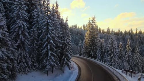 Aerial View of Winter Landscape with Snow Covered Mountain Hills and Winding Forest Road in Morning
