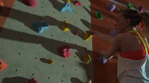 Woman Climbs Up Indoor Rock Climbing Wall