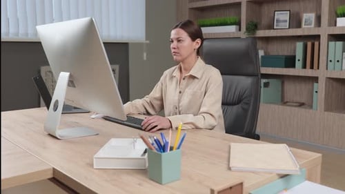 Woman Typing on Computer at Office Desk