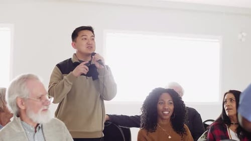 Man with microphone engages audience in community town hall discussion