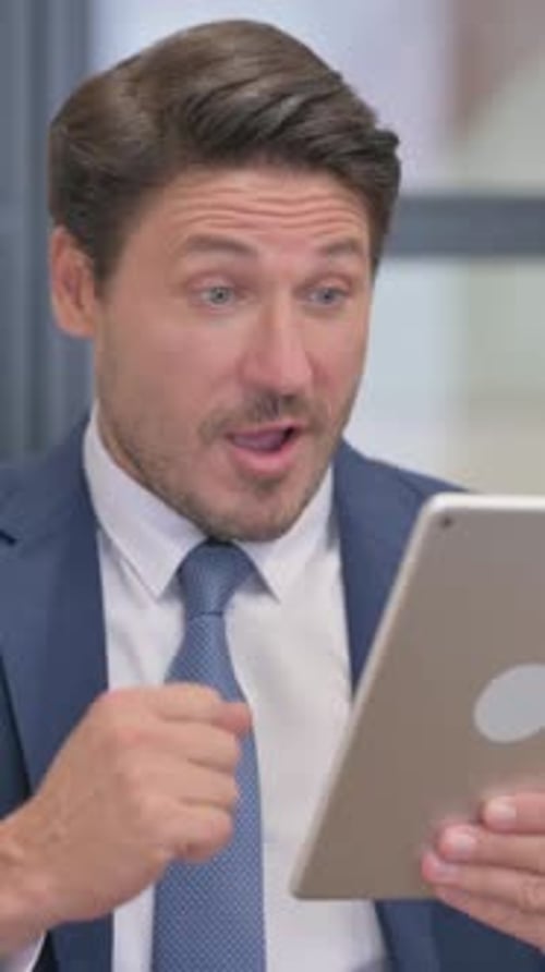 Excited Businessman Celebrating Success on Tablet Device
