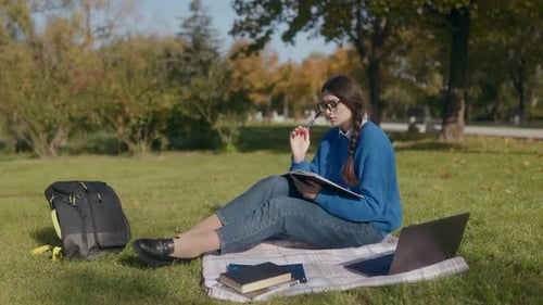 Woman Writing in Notebook in Sunny Park