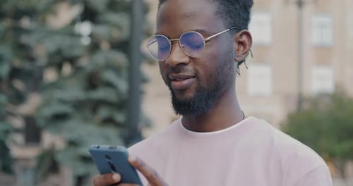 Young African American Student Using Smartphone Checking Social Media Standing Outside in City