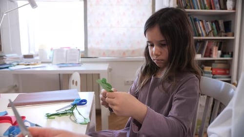 Young Girl Engaging in a Creative Paper Craft Activity at Home Demonstrating Focus and Developing
