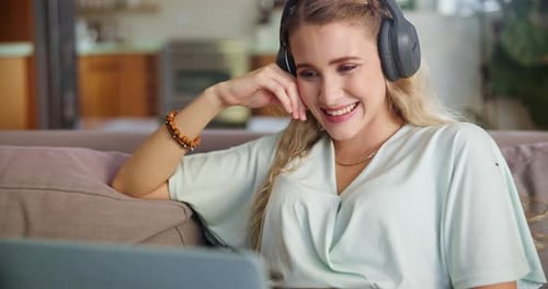 Woman Smiling and Watching a Laptop on Sofa