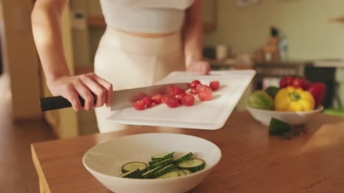 Close-up of young woman's hands preparing salad at home in the kitchen