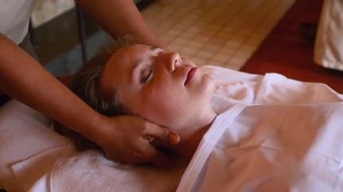 Junge Frau liegt und ruht sich auf dem Bett mit Kopfmassage und Behandlung aus