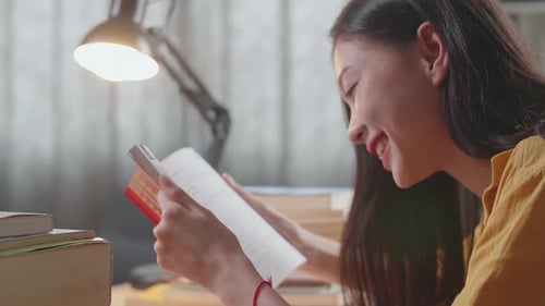 Close Up Of Young Asian Female Reading Books While Studying At Home