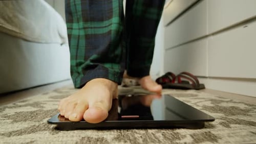 Bare Feet Stepping Onto Scale in Bedroom