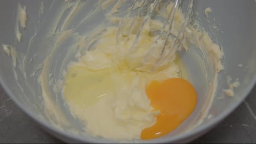 Frau mischt Ei zur Backzubereitung in Butter