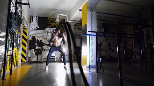 Muscular Afro American Sportsman Training with Battle Ropes at Fitness Centre Strong African Athlete