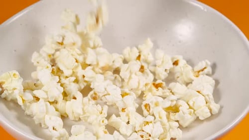 Tossing Salted Popcorn into a Ceramic Bowl. Shot with High Speed Camera. Slow Motion Snack