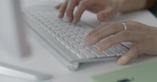 Hands Typing on Modern Silver Keyboard