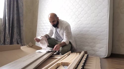 Man Assembling Furniture With Instructions Indoors