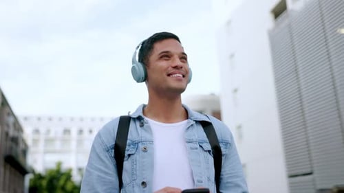 Happy, headphones and phone of a man in the city walking, listening and streaming music