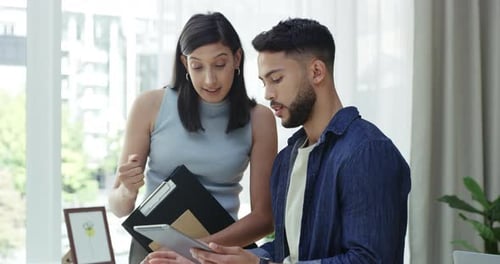 Female office manager talking and explaining an idea to a male employee on a tablet