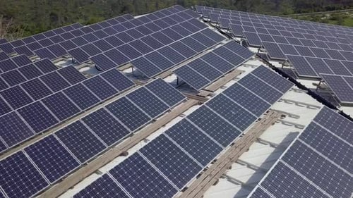 Solar panels spread across an industrial roof - Aerial footage.