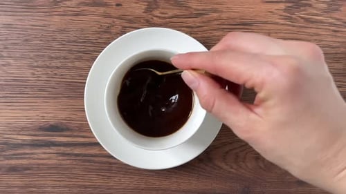 Stirring Coffee With Spoon in White Cup