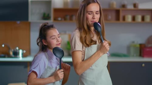 Woman and Girl Singing with Kitchen Utensils in Kitchen